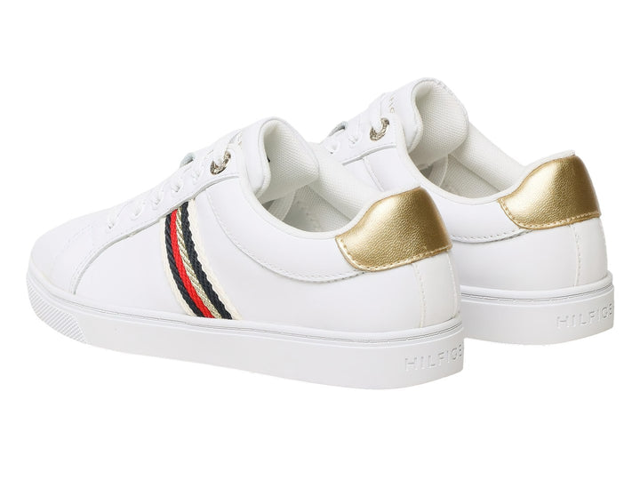 Tenis blancos Tommy Hilfiger con franja lateral tricolor y detalle dorado en el talón.