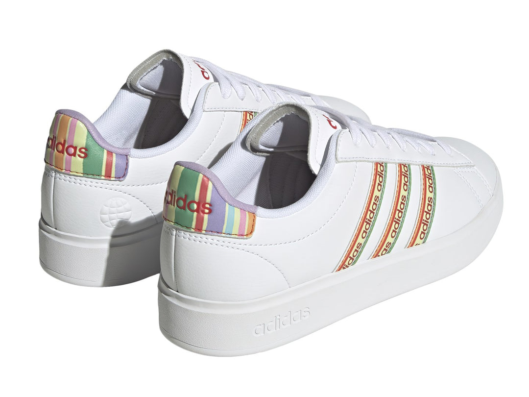 Tenis Adidas blancos con franjas laterales multicolor y suela blanca.