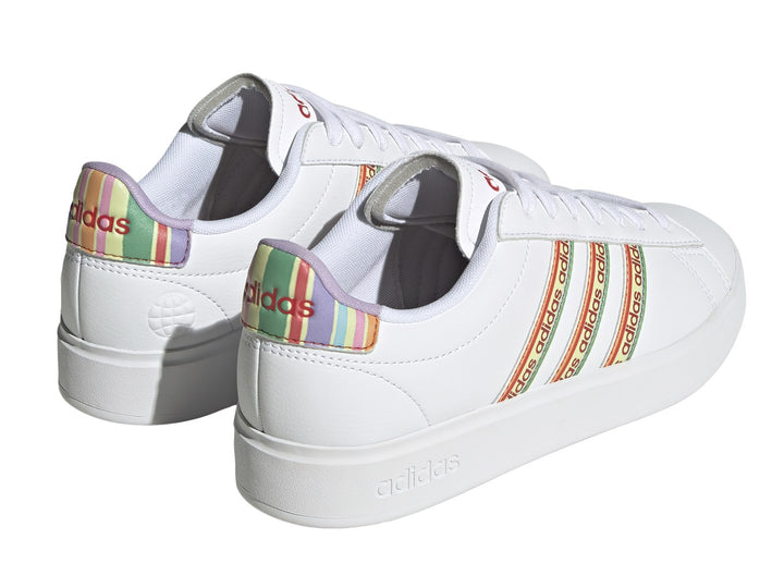 Tenis Adidas blancos con franjas laterales multicolor y suela blanca.