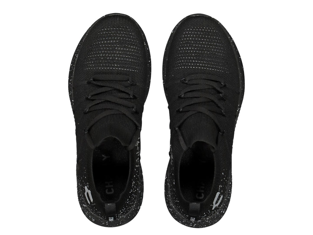 Tenis deportivos color negro con detalles moteados blancos en la suela.