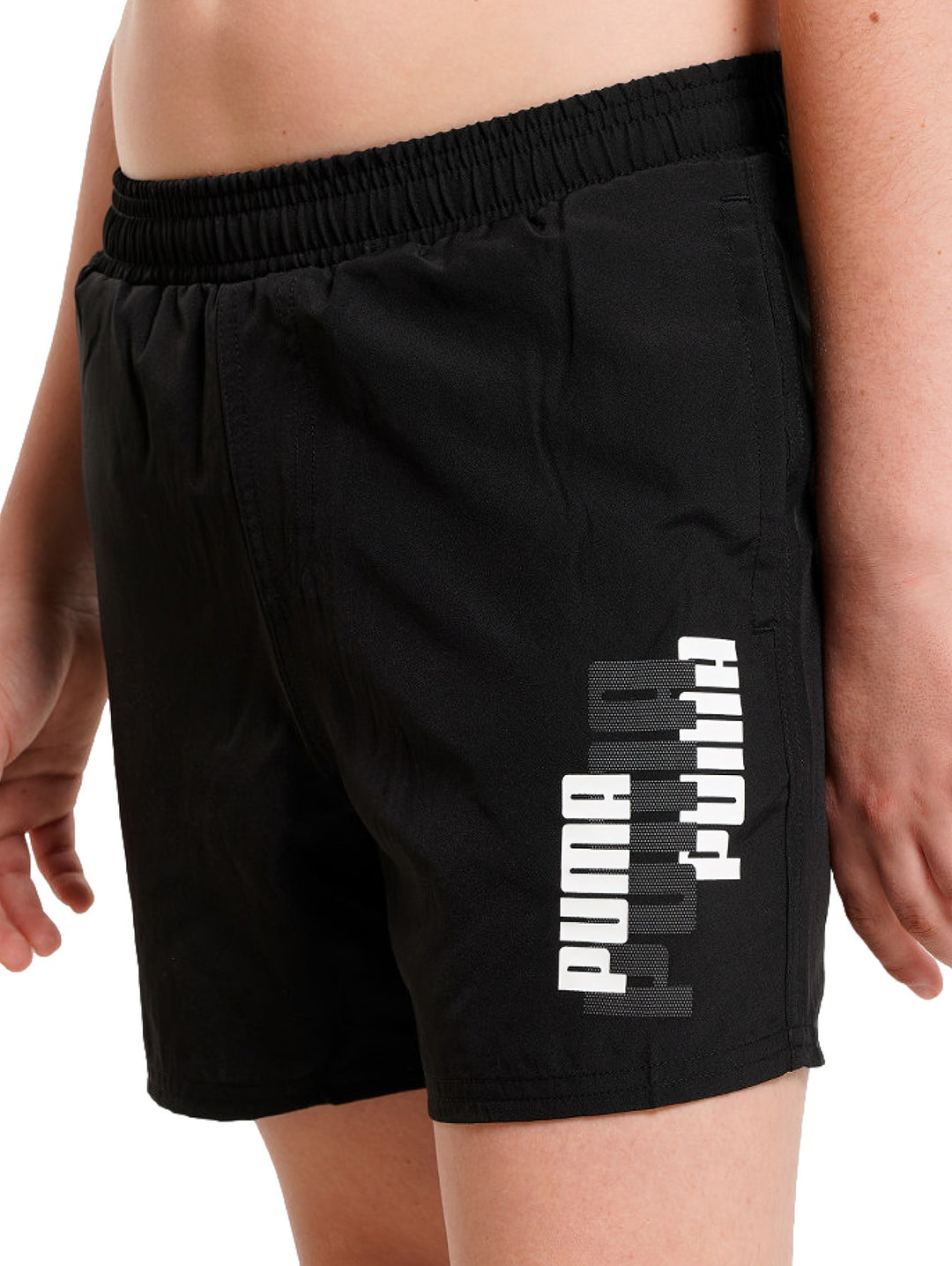 Shorts deportivos PUMA color negro con logotipo blanco y gris en la pierna izquierda, cintura elástica.