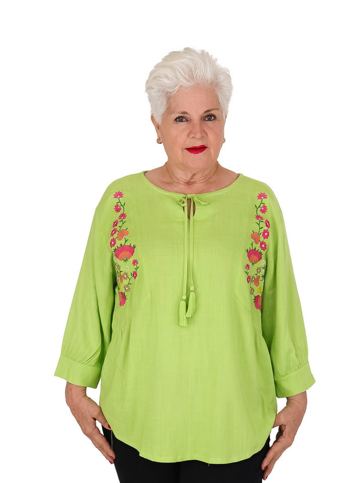 Blusa verde con bordados florales laterales y amarre en el cuello, manga 3/4.