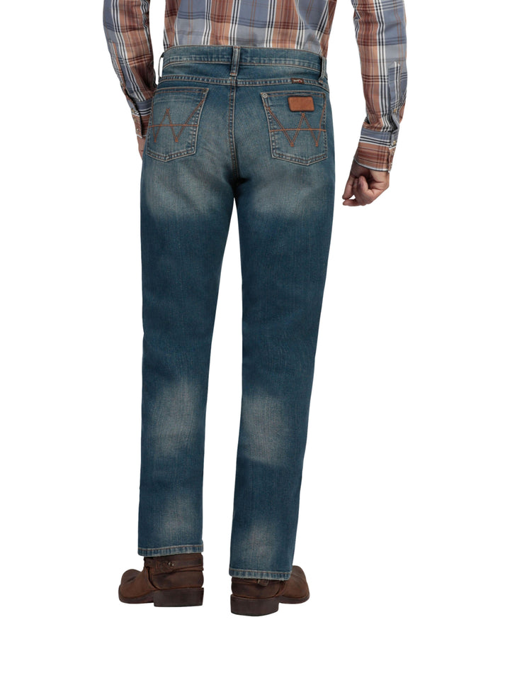 Hombre vistiendo pantalones Wrangler Stone Jeans Slim de color azul con efecto lavado.