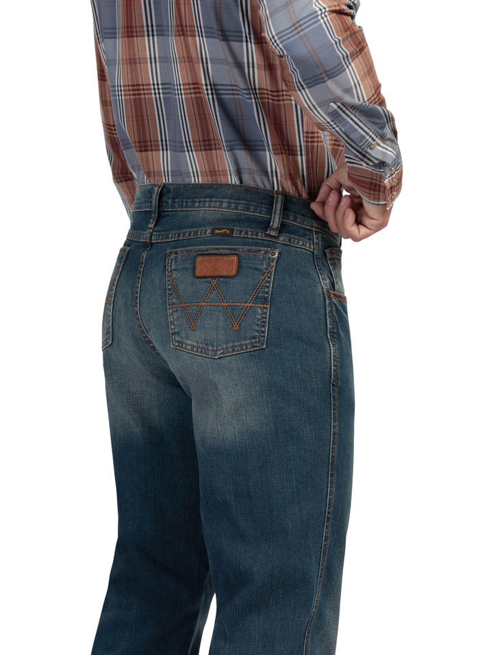 Hombre vistiendo pantalones Wrangler Stone Jeans Slim de color azul con efecto lavado.