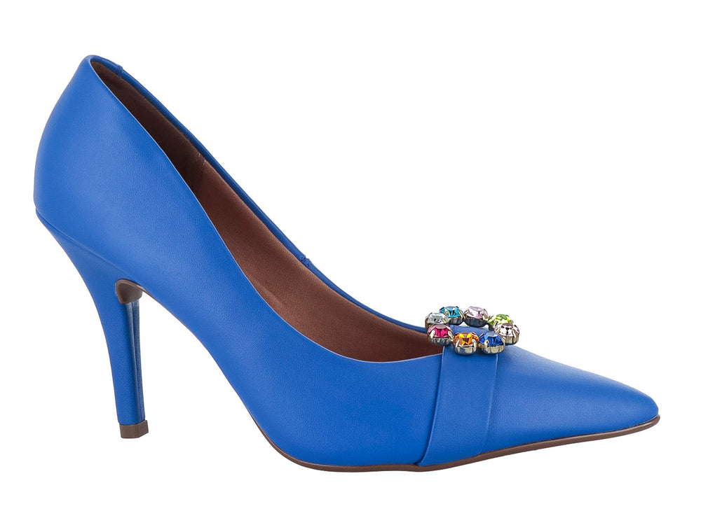Zapato de tacón alto color azul cobalto con un broche decorativo multicolor en la parte frontal.