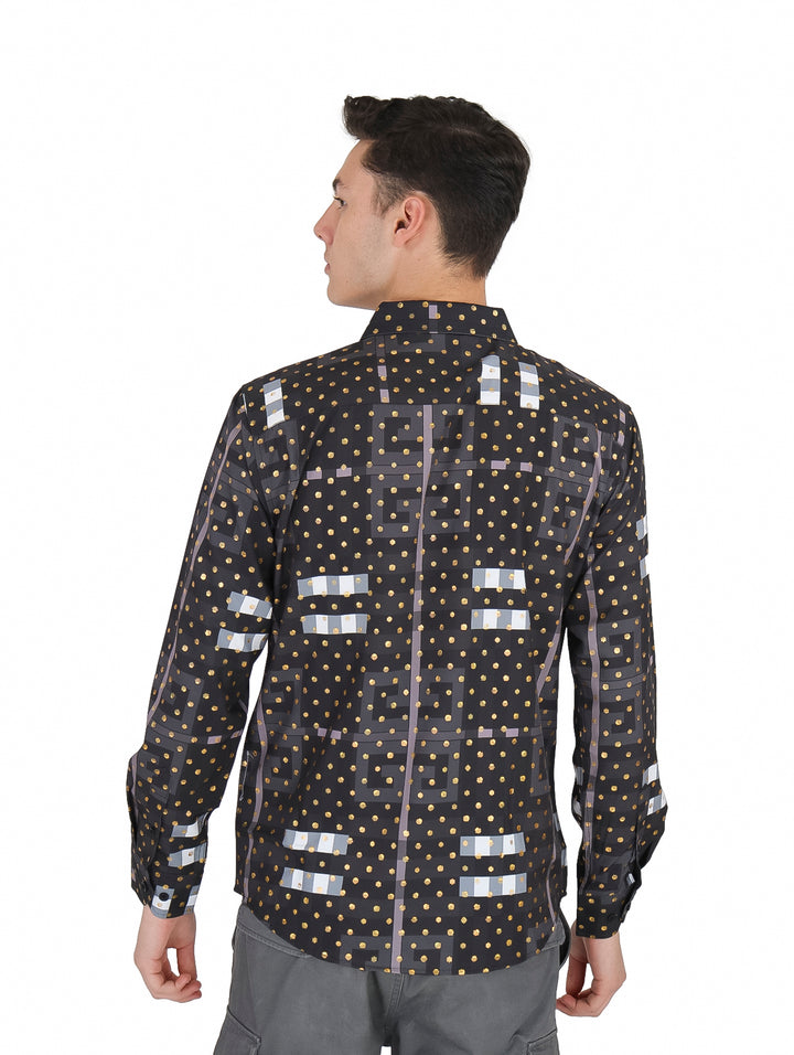 Hombre vistiendo camisa negra de manga larga con estampado de puntos dorados y figuras geométricas grises.
