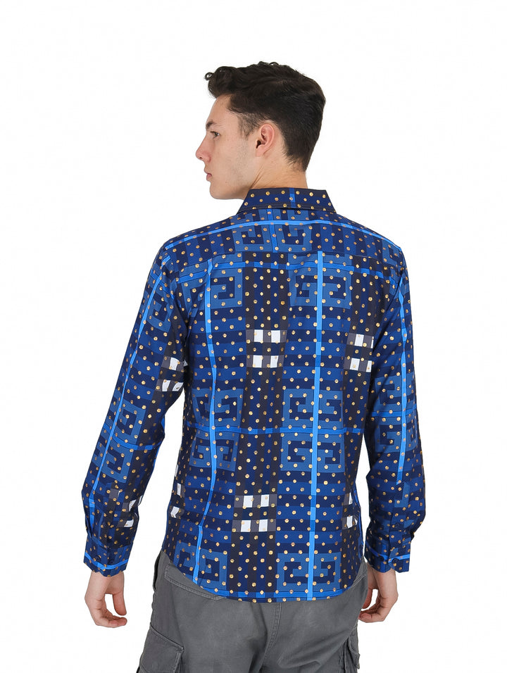 Hombre vistiendo camisa azul de manga larga con estampado de puntos dorados y figuras geométricas blancas.