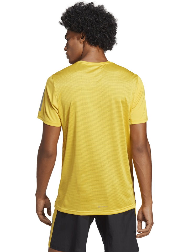 Hombre usando camiseta Adidas Own The Run color amarillo y shorts negros.