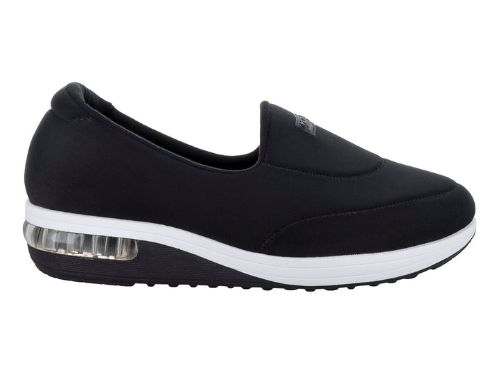 Zapato plano Modare color negro de tela lycra con suela blanca y amortiguador visible en el talón.