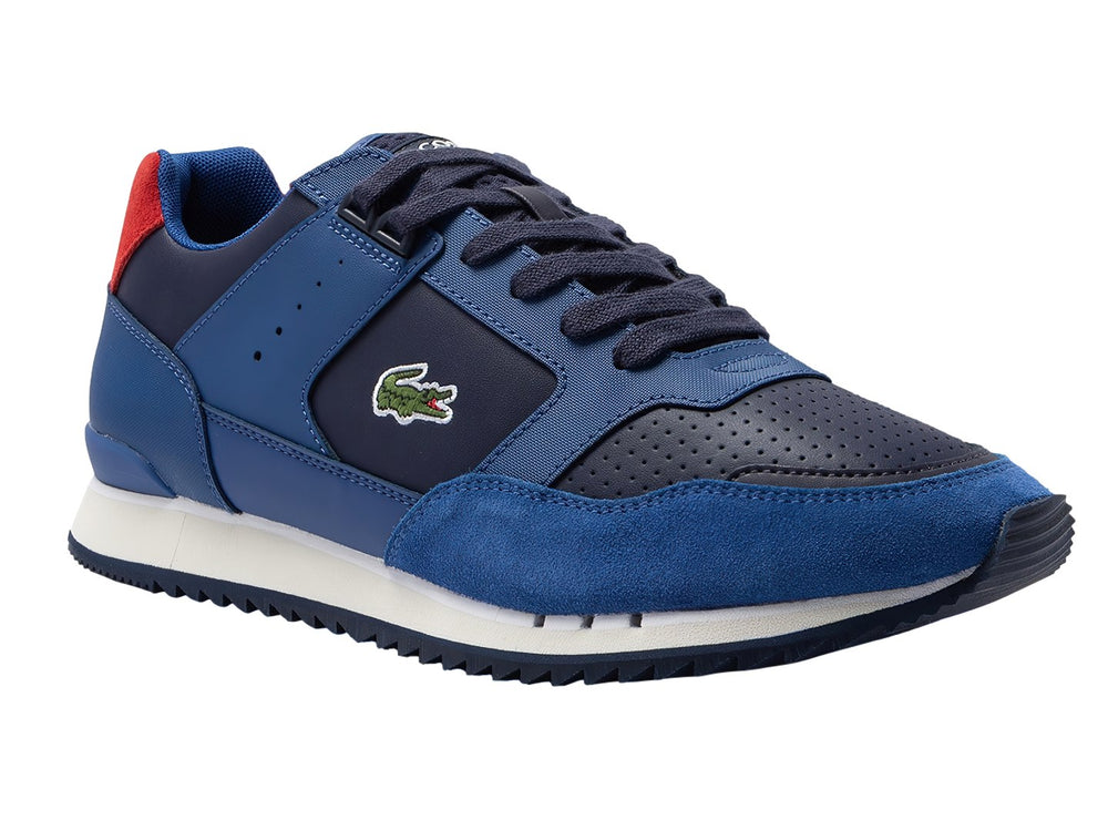 Tenis deportivos Lacoste en tonos azul y azul marino con suela blanca y detalle rojo en el talón.