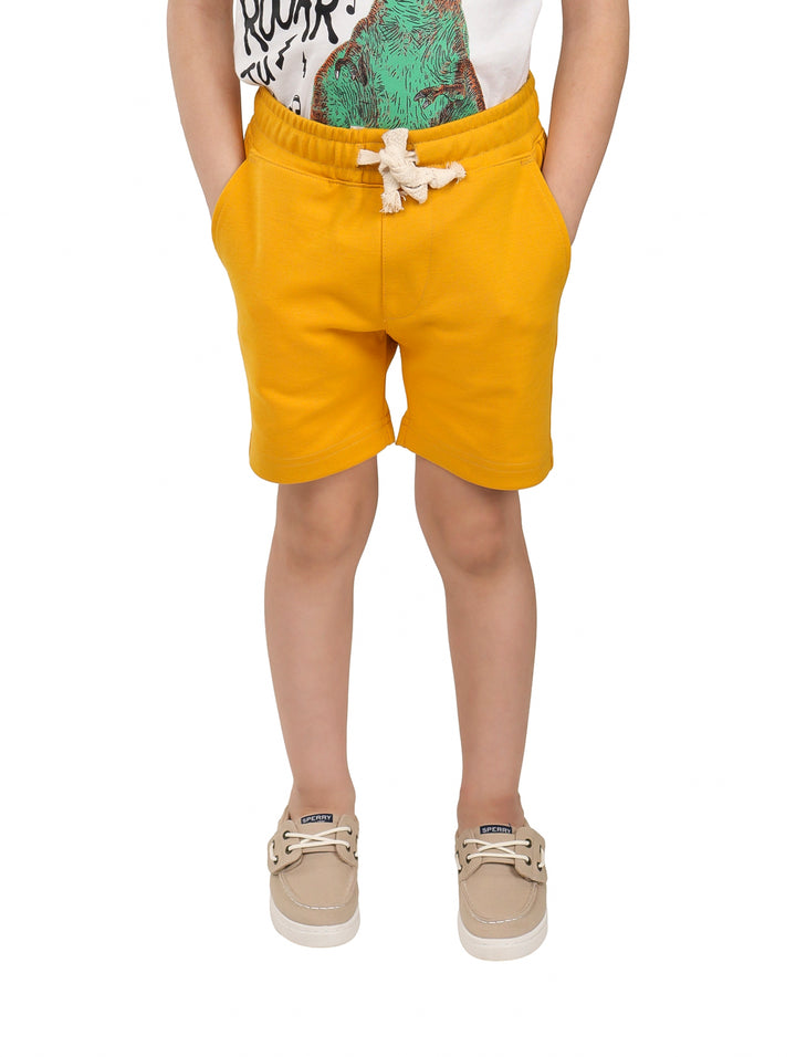 Niño vistiendo shorts color mostaza con cordón ajustable en la cintura.