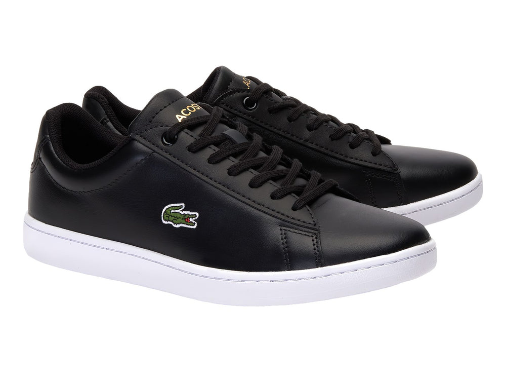 Tenis Lacoste color negro con suela blanca y logotipo del cocodrilo en el costado.