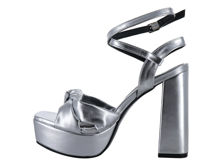 Sandalia de mujer color plata metálico con tacón grueso, plataforma y detalle de nudo en la parte frontal.