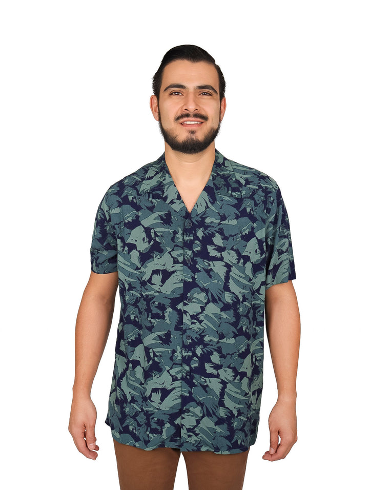 Hombre vistiendo camisa de manga corta con estampado floral en tonos verde y azul marino.