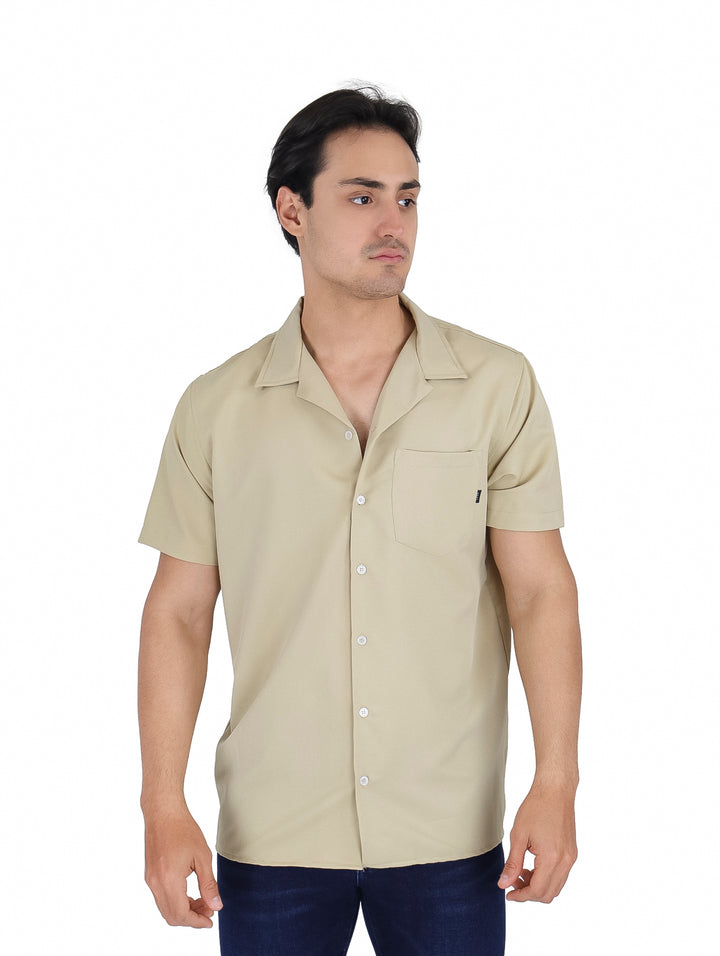 Hombre vistiendo una camisa beige de manga corta con botones y un bolsillo frontal.