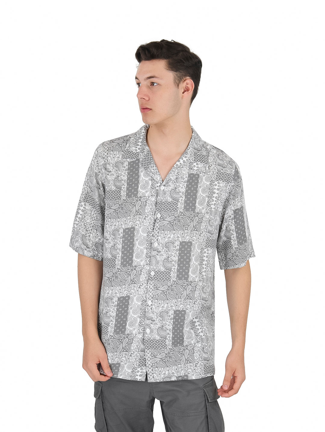 Hombre vistiendo una camisa de manga corta con estampado floral en tonos gris y blanco.
