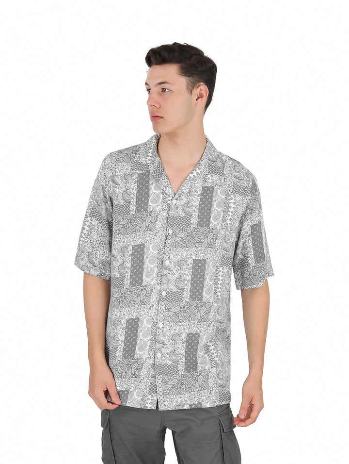 Hombre vistiendo una camisa de manga corta con estampado floral en tonos gris y blanco.
