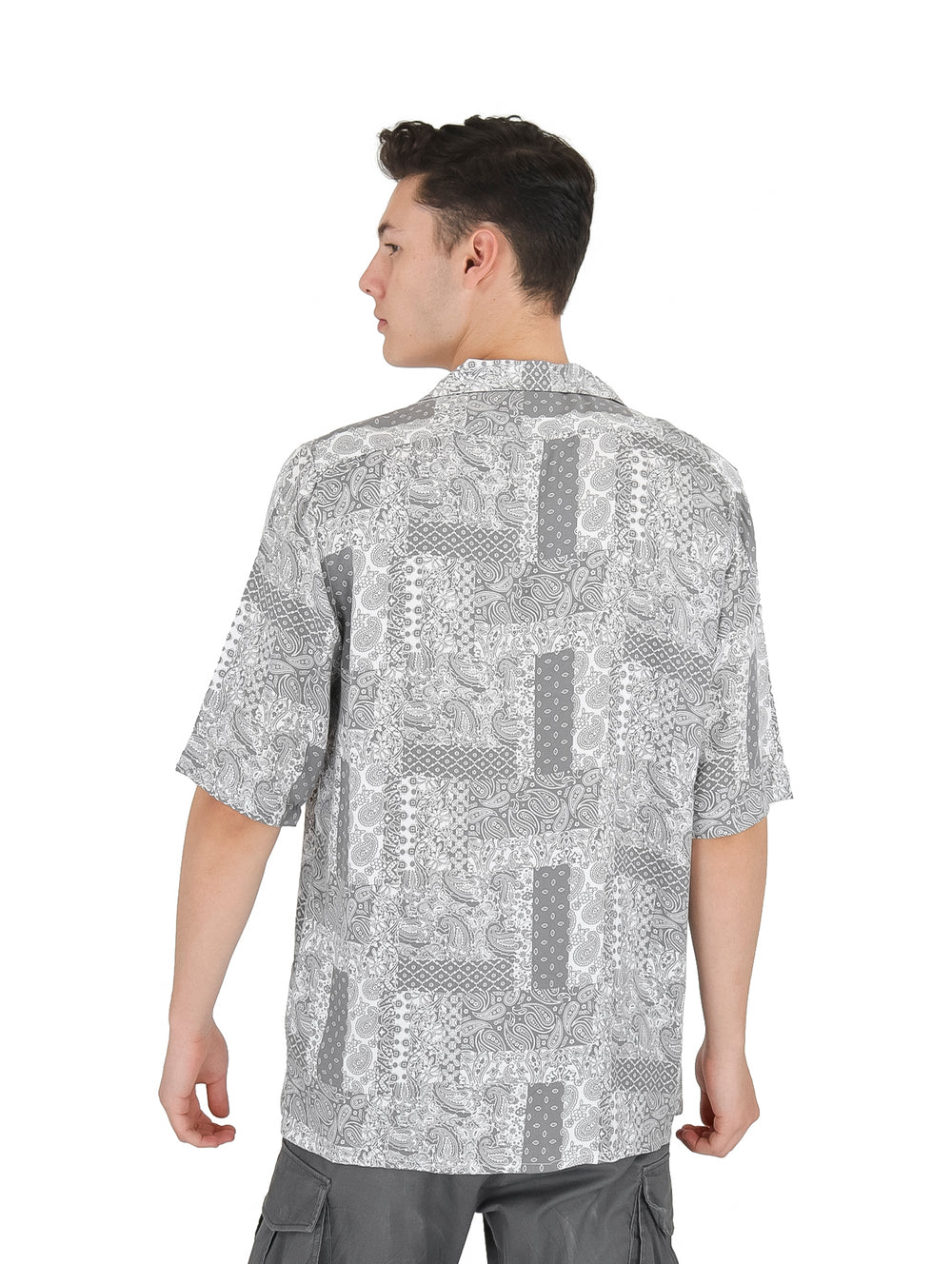Hombre vistiendo una camisa de manga corta con estampado floral en tonos gris y blanco.