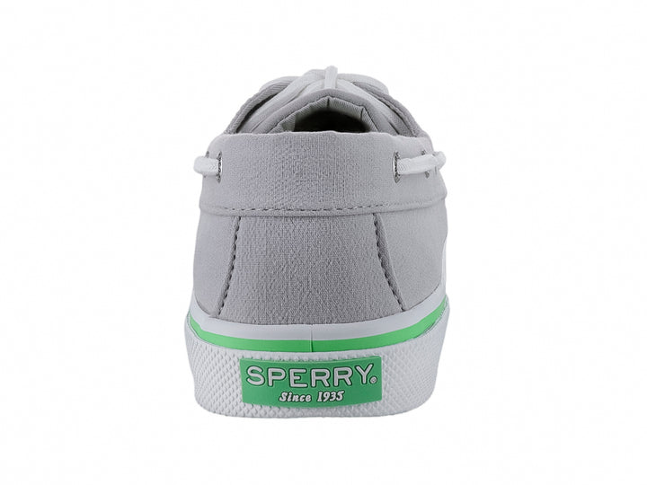 Zapato náutico Sperry de color gris con cordones blancos y una línea verde decorativa en la suela blanca.