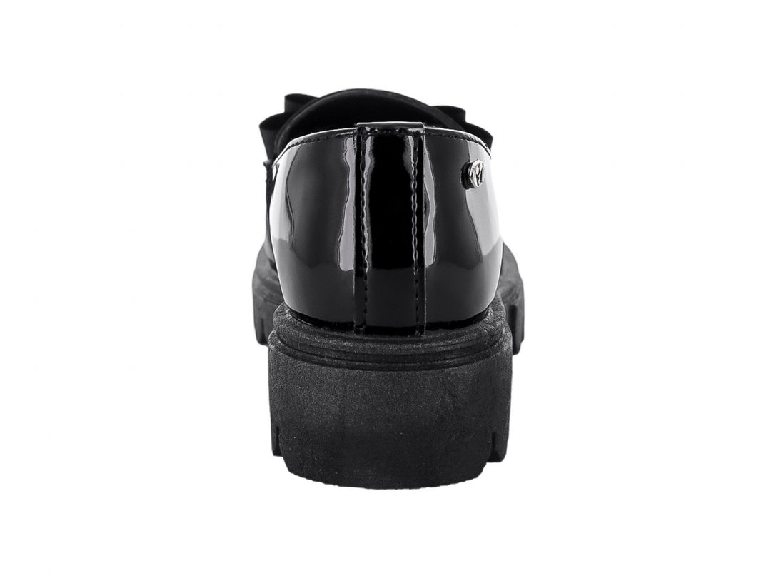 Zapato infantil tipo loafer de charol negro con moño y suela track gruesa.