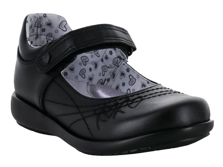 Zapato negro para niña de material sintético con correa de cierre y forro interior estampado de corazones.