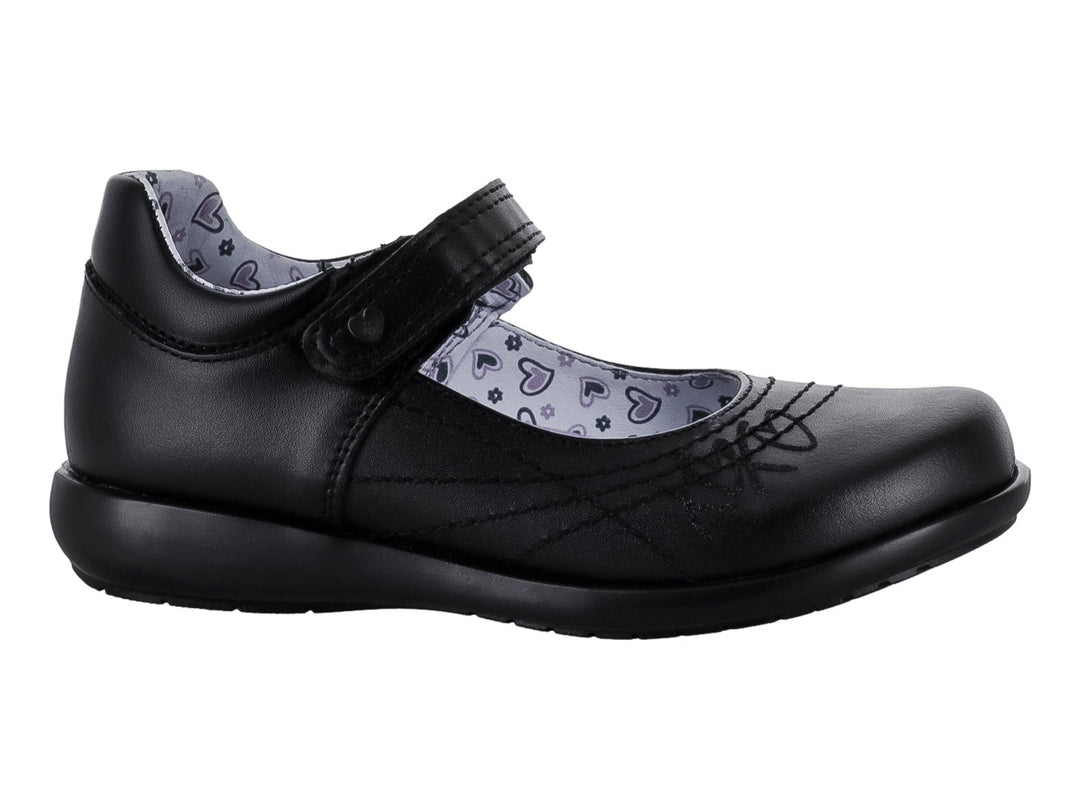 Zapato negro para niña de material sintético con correa de cierre y forro interior estampado de corazones.