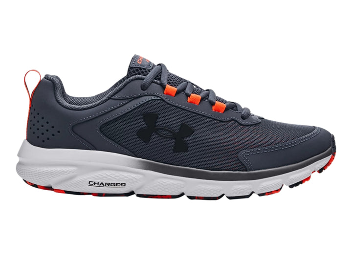 Tenis deportivos Under Armour color gris con suela blanca y detalles en naranja.