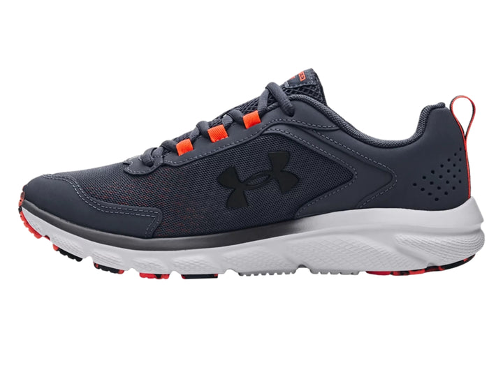Tenis deportivos Under Armour color gris con suela blanca y detalles en naranja.
