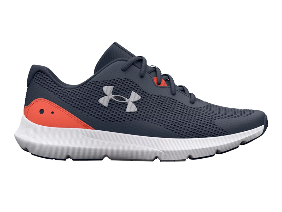 Tenis deportivos Under Armour color gris con suela blanca y detalle naranja en el talón.