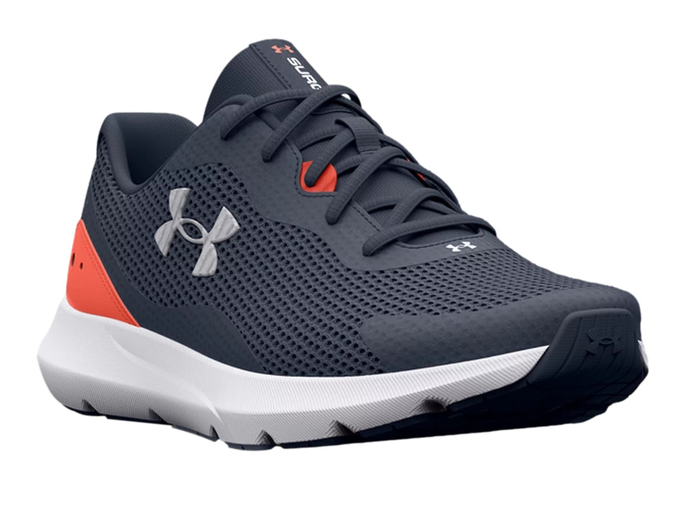 Tenis deportivos Under Armour color gris con suela blanca y detalle naranja en el talón.