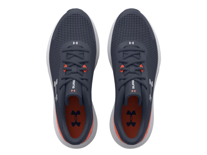 Tenis deportivos Under Armour color gris con suela blanca y detalle naranja en el talón.