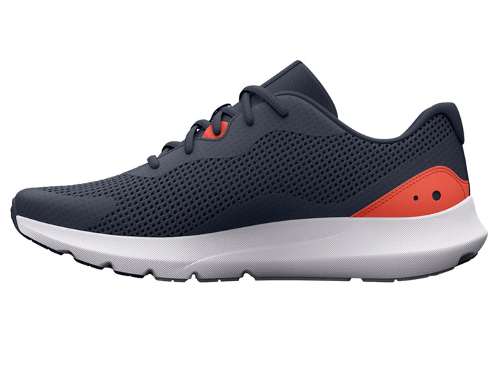 Tenis deportivos Under Armour color gris con suela blanca y detalle naranja en el talón.