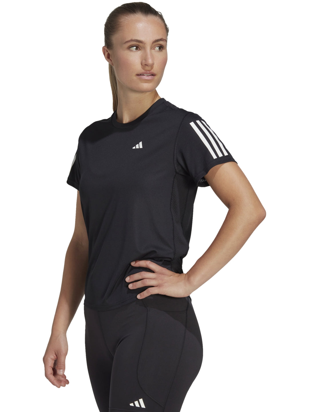 Mujer vistiendo camiseta deportiva Adidas color negro con detalles blancos en los hombros.