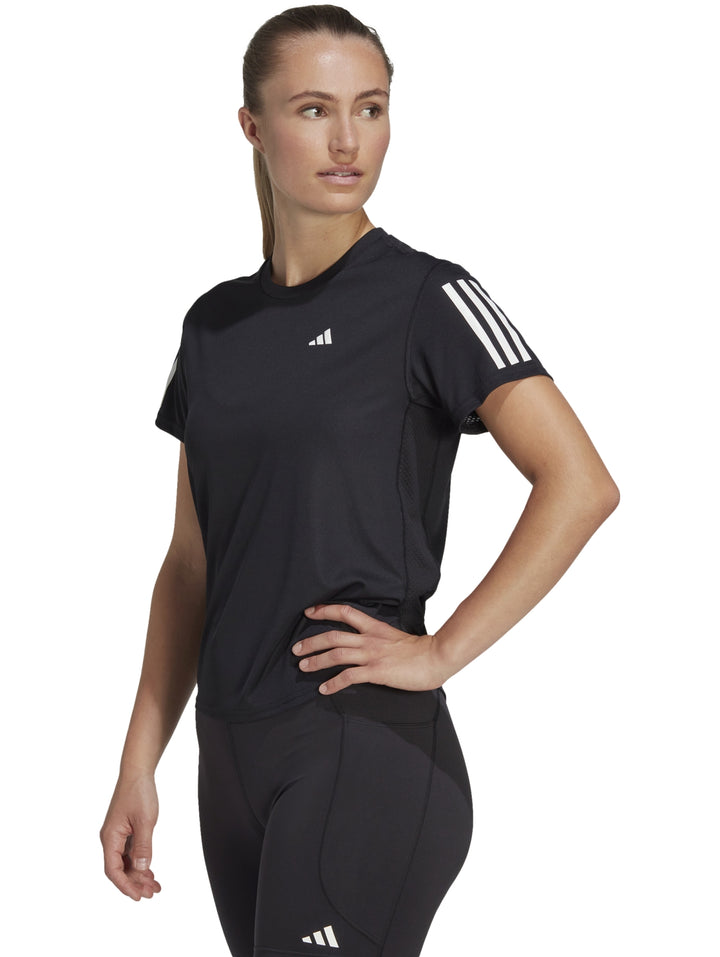 Mujer vistiendo camiseta deportiva Adidas color negro con detalles blancos en los hombros.