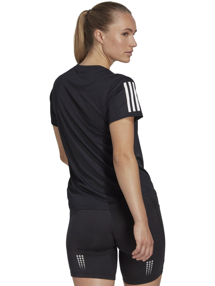 Mujer vistiendo camiseta deportiva Adidas color negro con detalles blancos en los hombros.