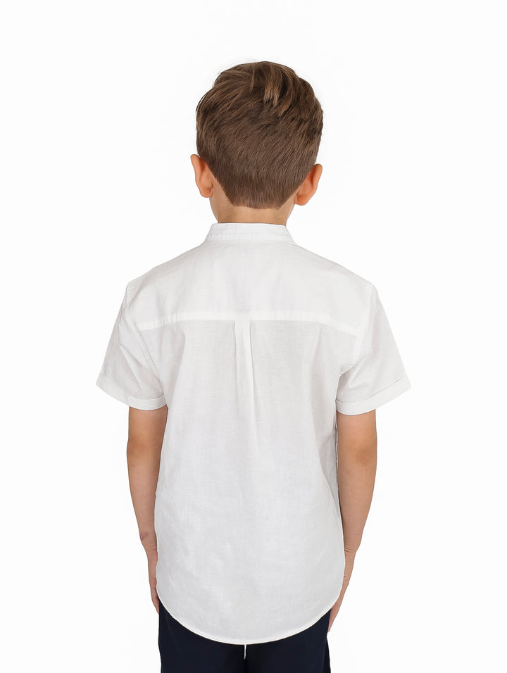 Niño vistiendo una camisa blanca de manga corta con cuello mao y botones frontales.