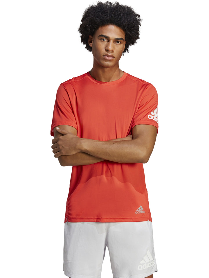 Hombre vistiendo camiseta deportiva Adidas de color rojo brillante con cuello redondo y manga corta.