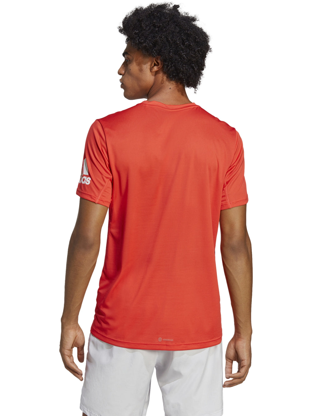 Hombre vistiendo camiseta deportiva Adidas de color rojo brillante con cuello redondo y manga corta.