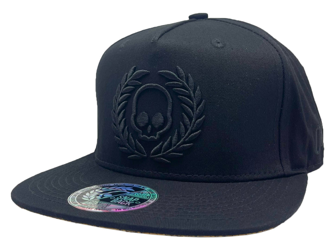 Gorra snapback color negro con diseño de calavera y laureles en relieve frontal.