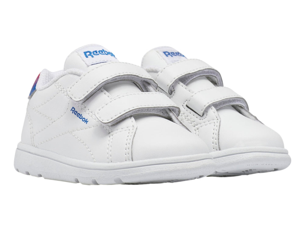 Tenis deportivos blancos Reebok para niño con cierres de velcro y detalle degradado en rojo y azul en el talón.