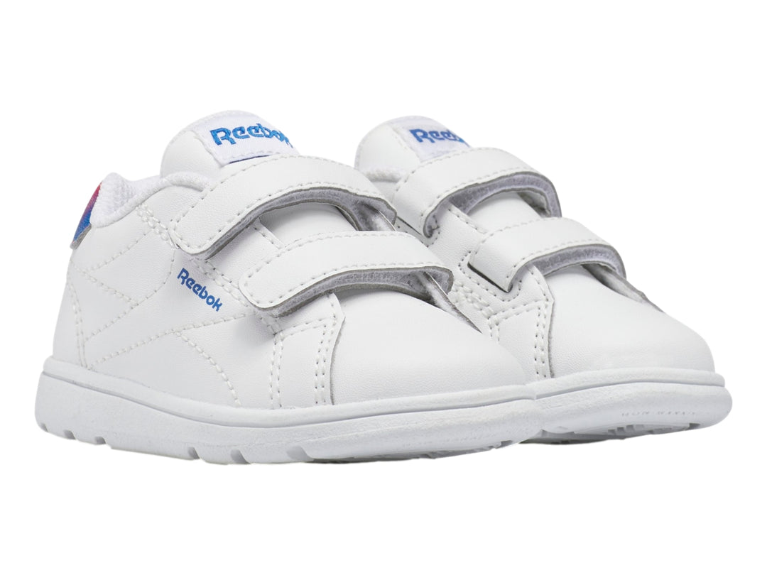 Tenis deportivos blancos Reebok para niño con cierres de velcro y detalle degradado en rojo y azul en el talón.