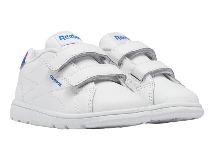 Tenis deportivos blancos Reebok para niño con cierres de velcro y detalle degradado en rojo y azul en el talón.