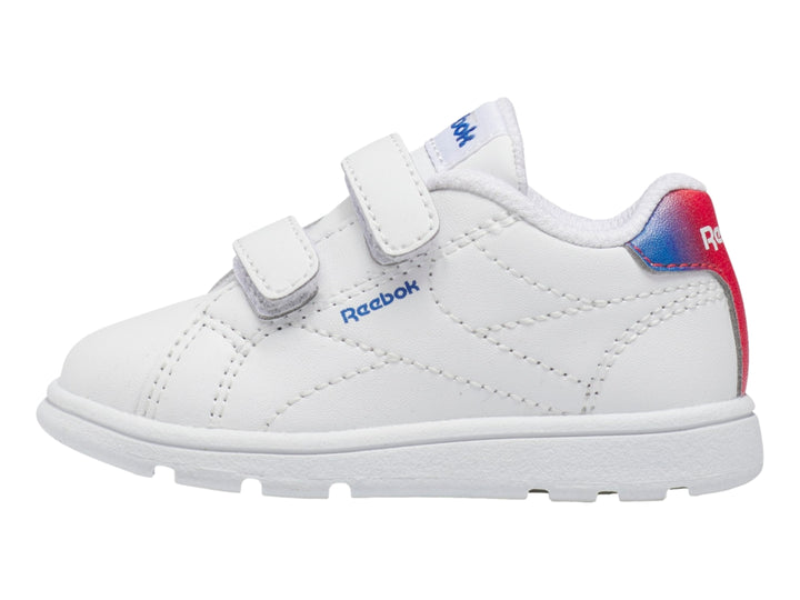Tenis deportivos blancos Reebok para niño con cierres de velcro y detalle degradado en rojo y azul en el talón.