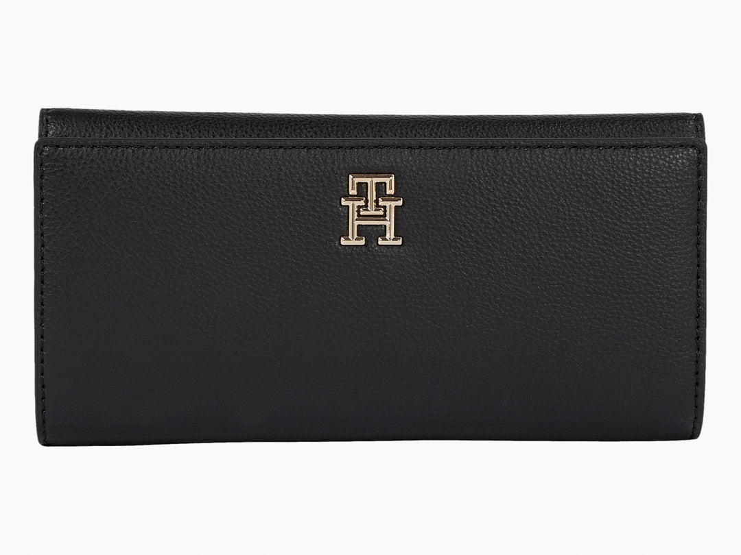Bolso estilo cartera color negro de cuero con logotipo dorado de Tommy Hilfiger al centro.