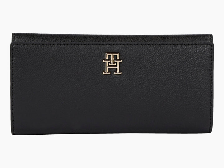 Bolso estilo cartera color negro de cuero con logotipo dorado de Tommy Hilfiger al centro.