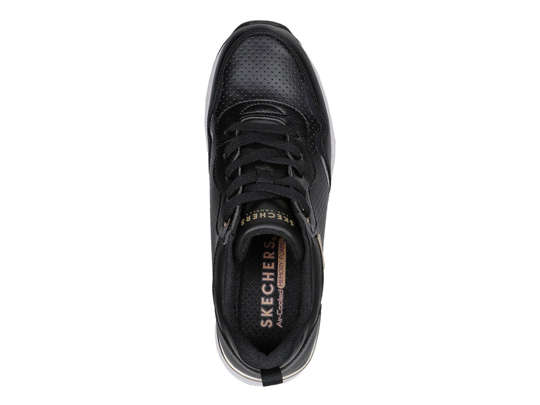 Tenis Skechers negros con suela blanca y detalles dorados.