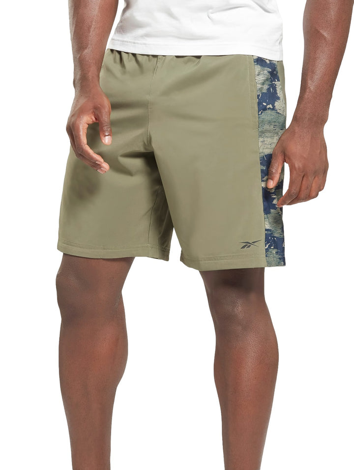 Shorts deportivos Reebok color verde con franja lateral de patrón camuflaje azul.