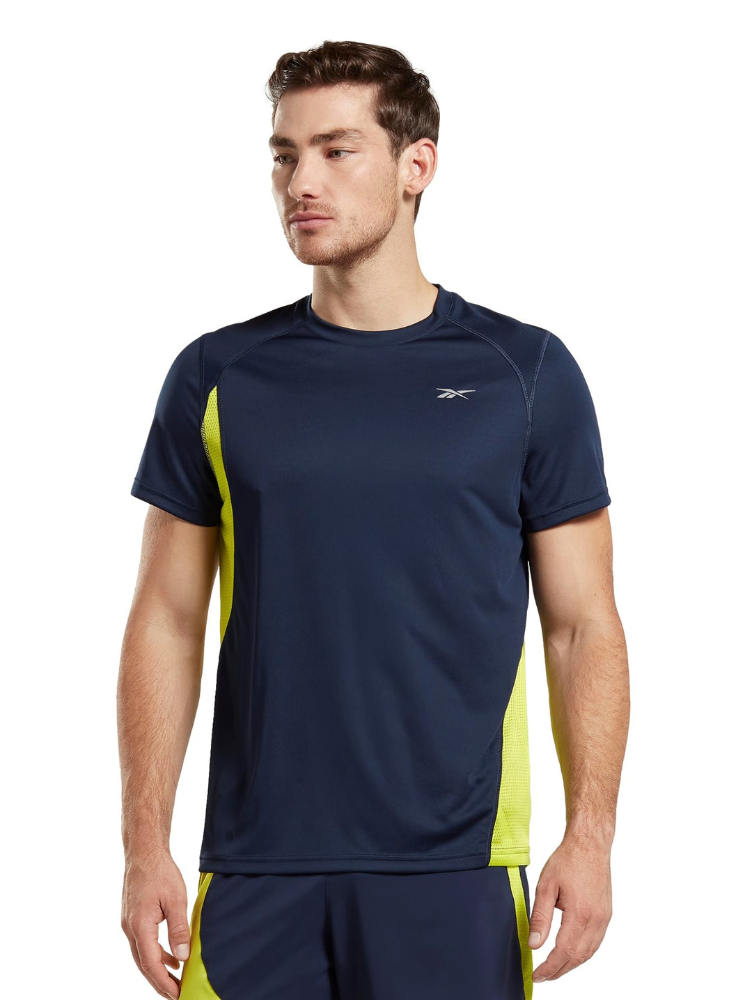 Hombre vistiendo camiseta deportiva Reebok color azul marino con detalles laterales en amarillo neón.