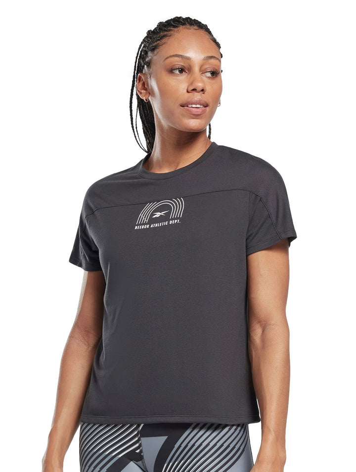 Mujer vistiendo playera deportiva Reebok de color negro con logotipo blanco en el pecho.