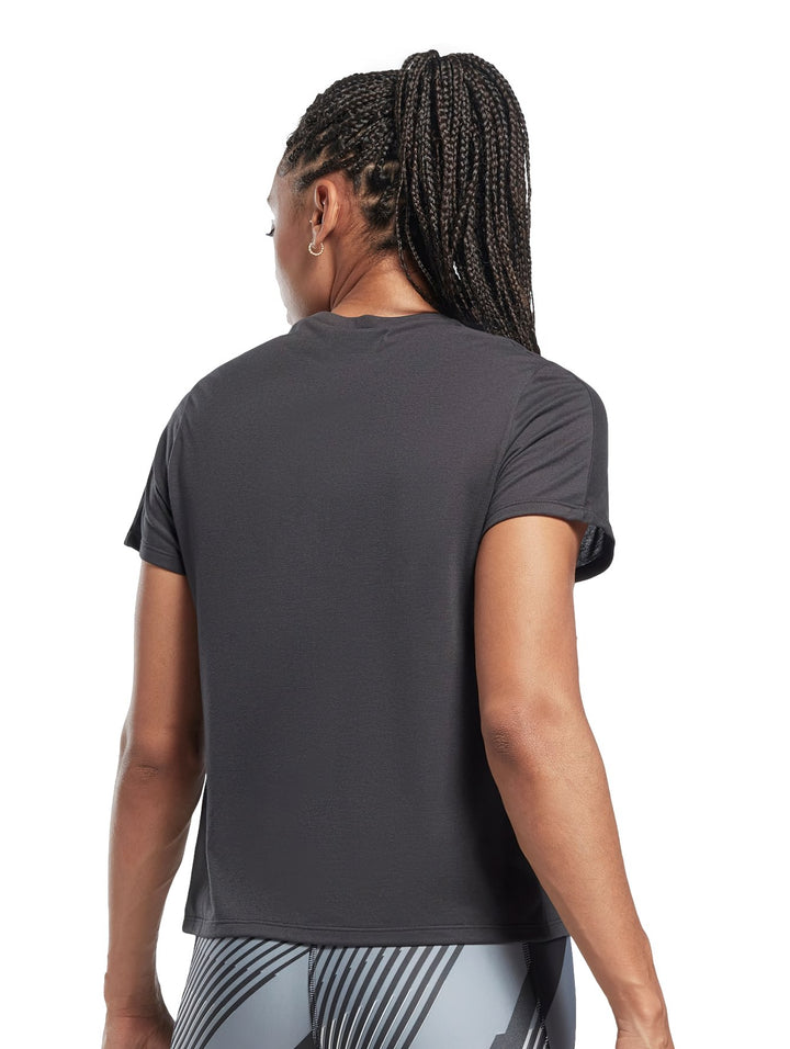Mujer vistiendo playera deportiva Reebok de color negro con logotipo blanco en el pecho.